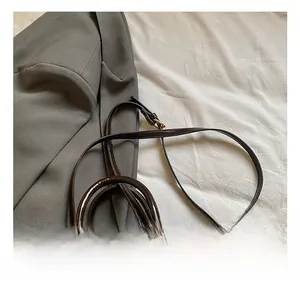 Detail of dark brown glossy handbag with adjustable strap and decorative polka dot scarf