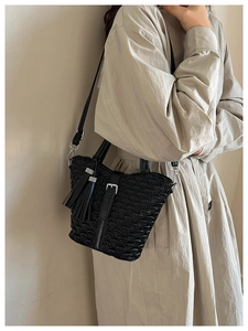 Close-up of black pleated bucket bag featuring geometric texture and tassel with silver rhinestones