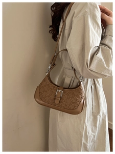 Detail of dark brown shoulder bag with vintage geometric embossing and silver buckle