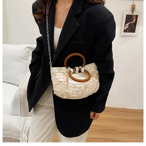 Detailed view of sequin crossbody bag with wood handles and silver metal chain strap