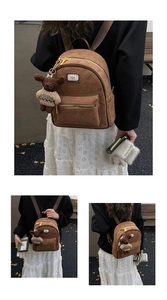 Detail eines braunen Wildleder-Rucksacks mit geprägten Figuren-Mustern und Bären-Anhänger