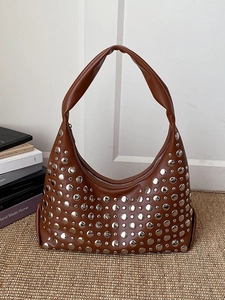 Sac seau sous le bras en cuir marron avec rivets argentés sur fond tissé épuré