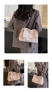 Detail of a light pink pleated tote bag with silver chain strap shown in a casual lifestyle setting