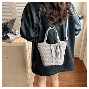 Detail of cream woven bucket bag with 3D pleated texture and elegant double tassels
