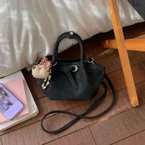 Détail du sac cabas en daim noir avec boucle en cuir et adorable pendentif ours