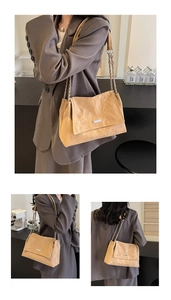 Detail of light khaki shoulder bag featuring pleated leather texture and silver chain strap