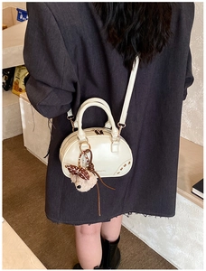 Detail of a cream Boston bag with 'MANMAN & BAG' text and a cute teddy bear pendant