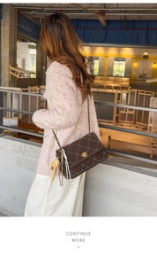 Detail of dark brown quilted bag with gold chain strap, twist lock, and bear charm