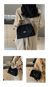 Detail of black pleated tote bag with metal chain strap and rectangle logo plaque