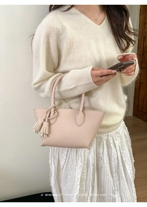 Detail of pink leather handbag with decorative tassels styled with minimalist knitwear