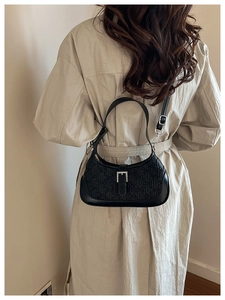Detail of black faux leather shoulder bag featuring bear embossed pattern and silver buckle
