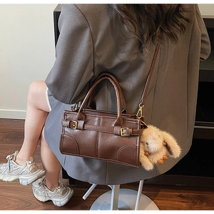 Detail of dark brown vintage handbag with gold buckles and a plush rabbit charm