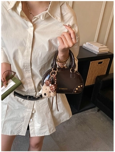 Detail of retro dark brown mini pillow bag with golden rivets and cute bear charm