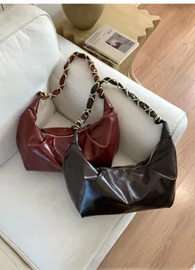 Close-up of hobo shoulder bags in glossy burgundy and dark brown with metal chain straps