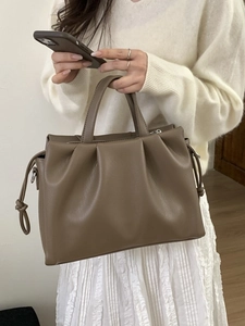 Sac cabas plissé kaki foncé en cuir fin, porté par un mannequin dans un style élégant