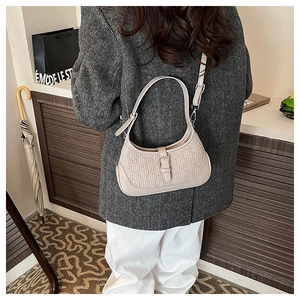 Close-up of beige shoulder bag with embossed texture and adjustable metallic buckle strap