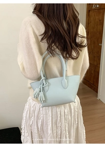 Detail of light blue leather bucket bag with fringe tassel and minimalist retro texture