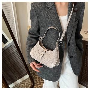 Close-up of the textured beige shoulder bag with embossed chain patterns on the strap