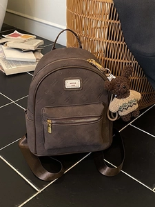 Modischer brauner geprägter Reise-Rucksack mit Bärenanhänger auf Fliesenboden