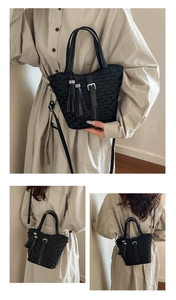 Detail of black quilted bucket bag with double tassel charms and silver buckle strap