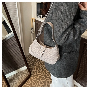 Detail of a beige textured monogram shoulder bag with adjustable leather strap