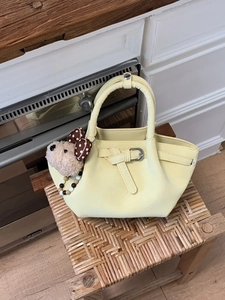 Sac seau plissé jaune crème élégant avec pendentif ours sur tabouret en osier