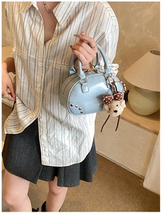 Detail of light blue vintage mini bag with gold rivets and cute plush bear pendant