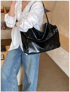 Detail of black faux leather tote bag with silver metal rivets and spacious interior
