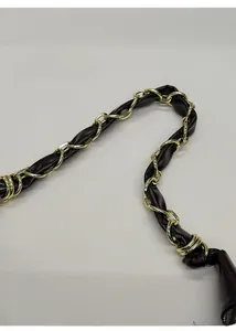 Detail of dark brown leather woven with gold metal chain strap and metal buckles