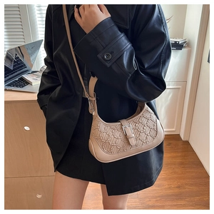 Detail of beige quilted shoulder bag featuring vintage embossed texture and silver buckle