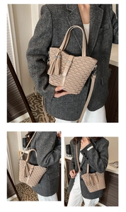 Detail of cream woven bucket bag showing top handle, tassel charm, and adjustable strap