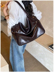 Detail view of large dark brown leather hobo bag showing glossy finish and slouchy shape