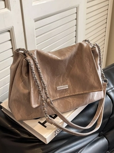 Borsa tote beige a pieghe con tracolla a catena e logo in metallo su base minimalista