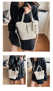 Detail view of white pleated bucket bag with tassel charms and silver metal hardware