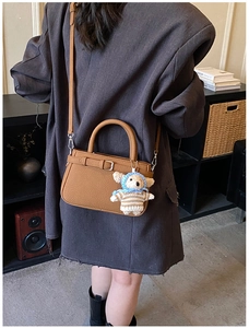 Close-up of brown pebbled leather handbag featuring a cute crochet bear bag charm