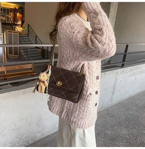 Detail of dark brown quilted chain crossbody bag with cute teddy bear charm pendant