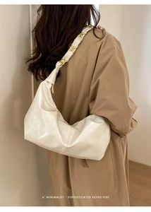 Detail of off-white retro hobo bag with gold chain woven shoulder strap on a model