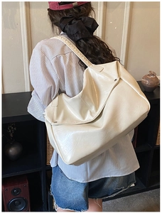 Detail of a large cream white glossy tote bag with wide strap for stylish commuting