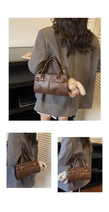 Detail view of deep brown vintage faux leather handbag with golden buckle and bunny charm