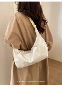 Detail of a minimalist cream hobo bag with metallic ring strap on a stylish model