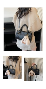 Detail view of black vintage leather bag with golden buckle and cute plush rabbit charm