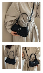 Detail showing embossed black faux leather shoulder bag with buckle and detachable strap