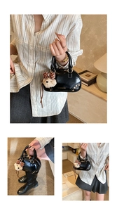 Detail of black patent leather mini Boston bag with metal rivets and bear charm
