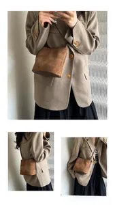 Detail of a vintage brown matte suede crossbody bag styled with a tailored blazer