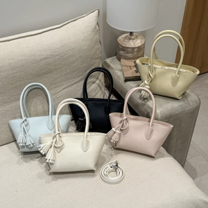 Detail of colorful trapezoid tote bags in litchi grain faux leather with tassel charms