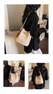 Détail du sac seau blanc cassé avec texture en cuir mat et pendentif en perles colorées