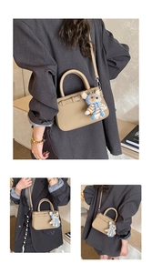 Detail of khaki leather rectangular handbag with a teddy bear charm and shoulder strap