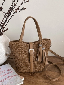 Vintage brown pleated bucket bag with tassel charms and top handle on a wooden table