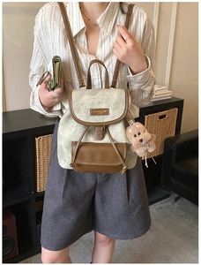 Close-up of retro gray-green frosted leather backpack with brown trim and plush bear charm