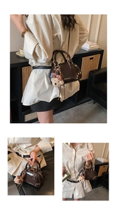 Detail of dark brown glossy Boston bag with rivet accents and plush bear charm